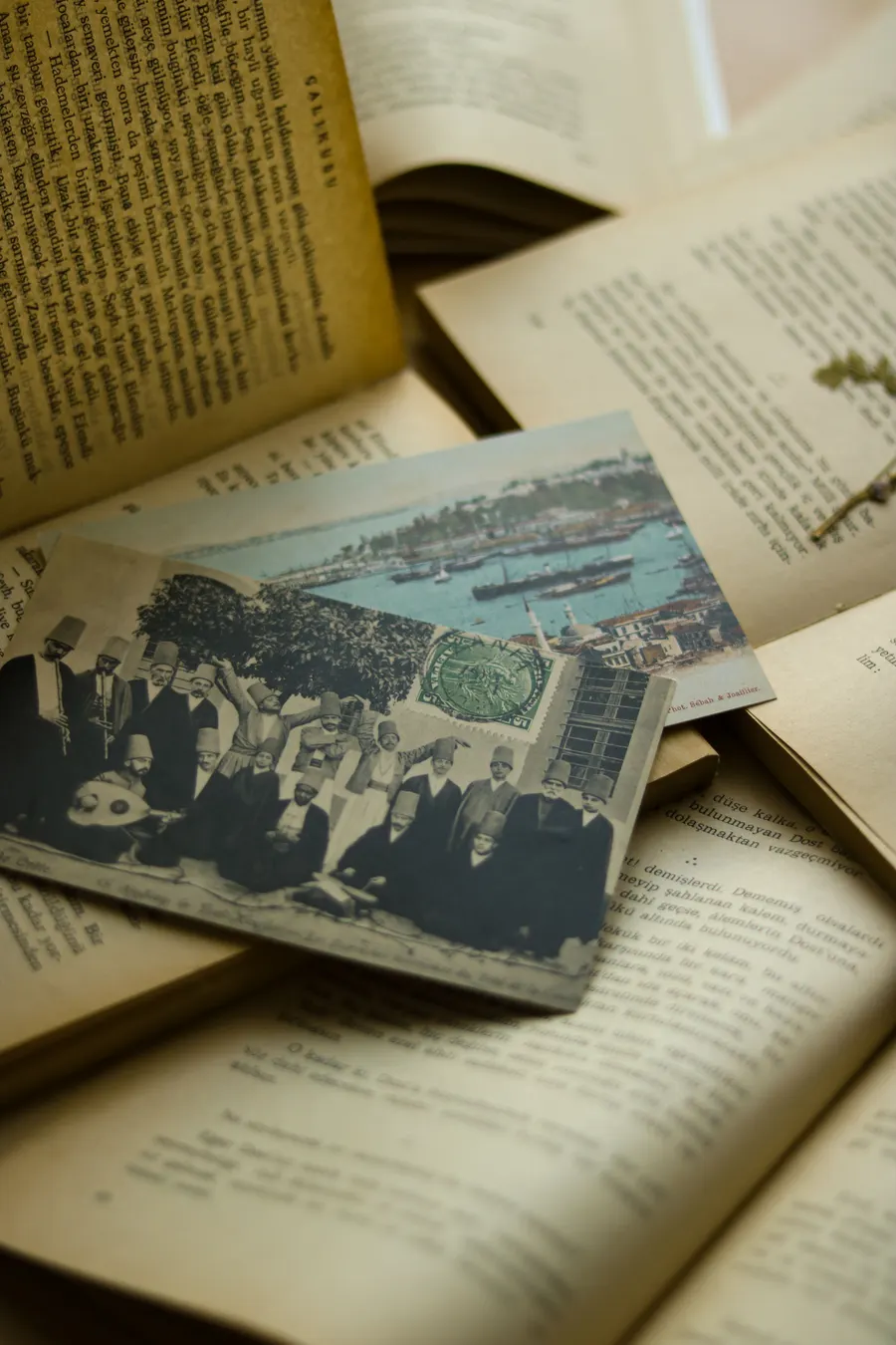 An antique postcard with a harbor scene resting on the pages of an old book