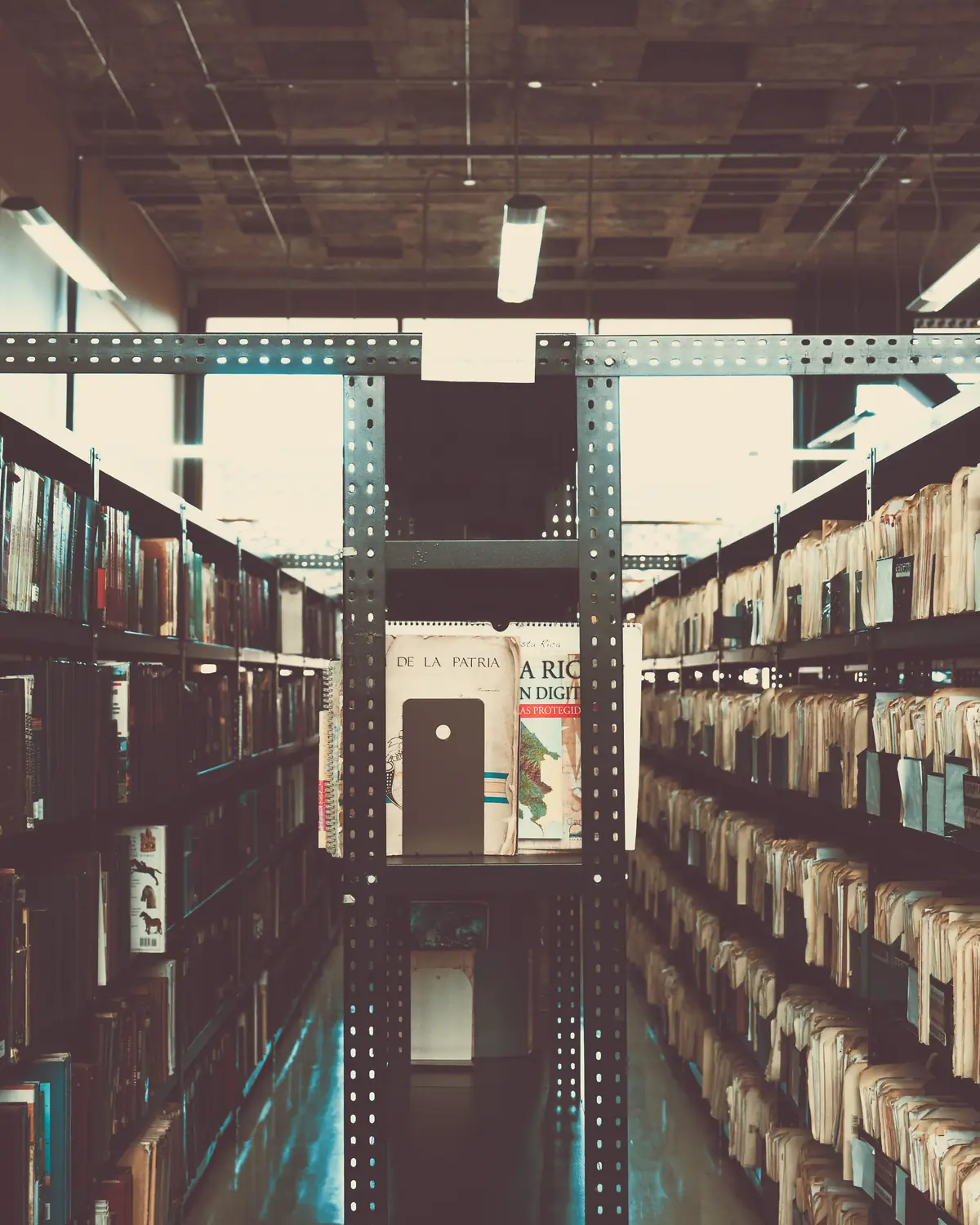 An aisle between tall metal archive shelves packed with bound documents