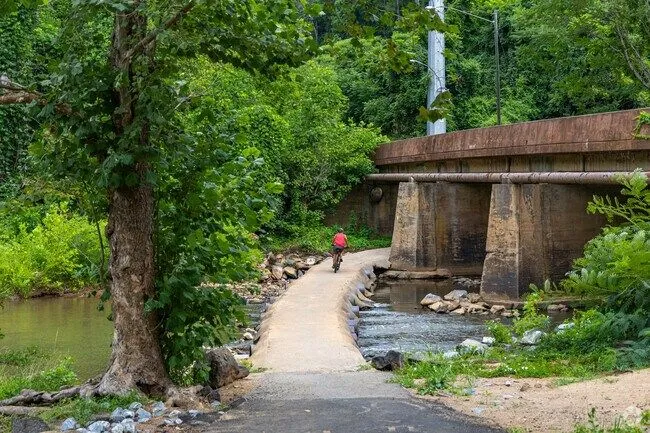 A tree-lined trail beside a creek at Hollins Mill Park in Lynchburg, Virginia